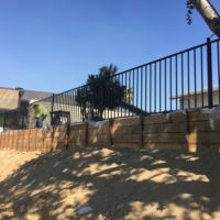 Timber retaining wall using steel posts as support. A wrought iron
fence was built on top so no one would walk oﬀ the edge.